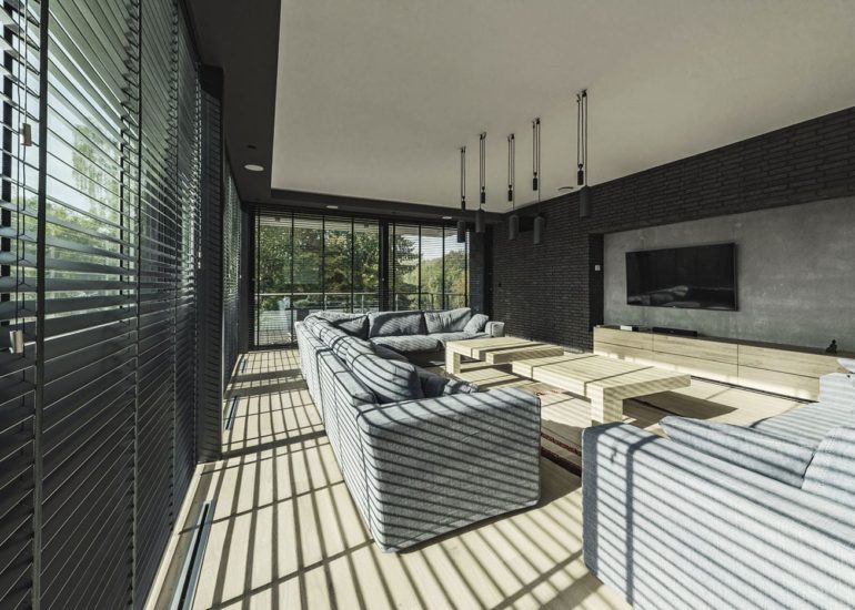 Wnętrze nowoczesnego salonu oświetlone przez słońce wpadające przez rolety