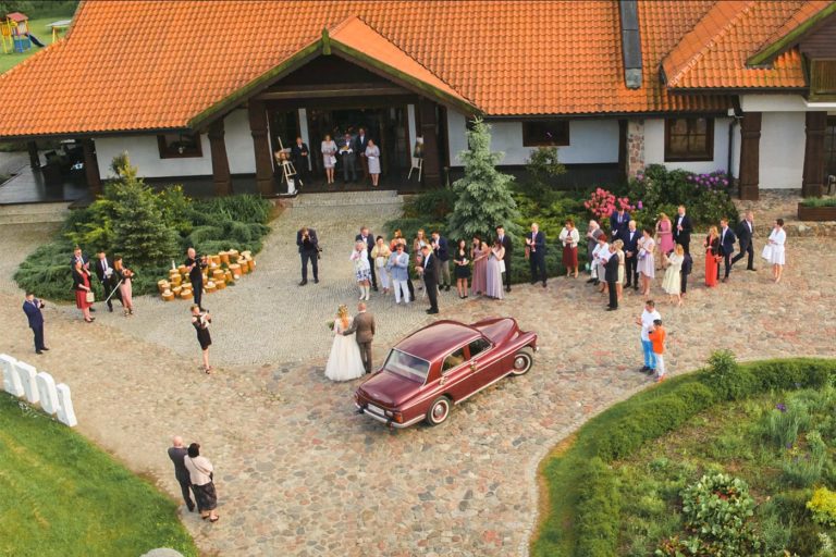 Ujęcie ślubne z drona - przywitanie gości pod salą weselną w województwie warmińsko-mazurskim dron na wesele
