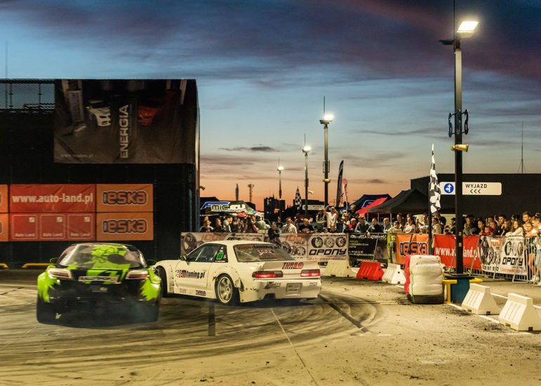 Samochody do driftu w trakcie przejazdu na imprezie Night Power w Olsztynie na tle zachodu słońca