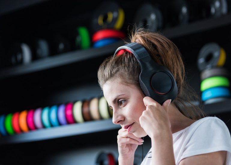 Kobieta zakładająca słuchawki wydrukowane w technologii druku 3d na kolorowym tle