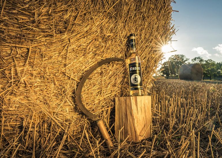 Butelka napoju przy beli siana i sierpie w trakcie sianokosów w województwie warmińsko-mazurskim