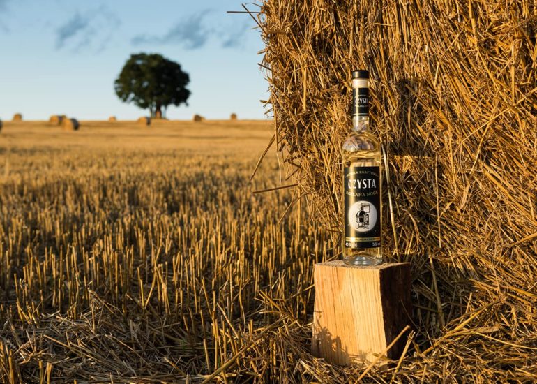 Butelka wódki przy beli siana w trakcie żniw - fotografia reklamowa Olsztyn