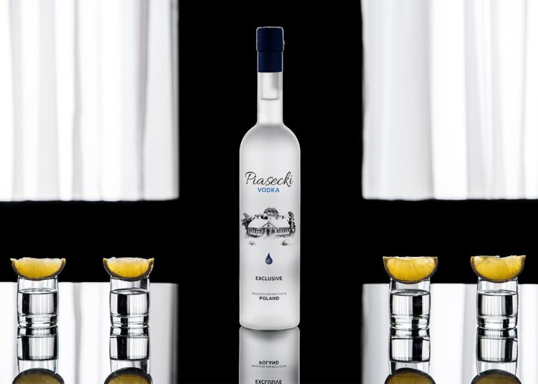 Butelka Piasecki Vodka z kieliszkami i cytryną na tle zasłoniętego okna w symetrycznej formie - zdjęcie reklamowe