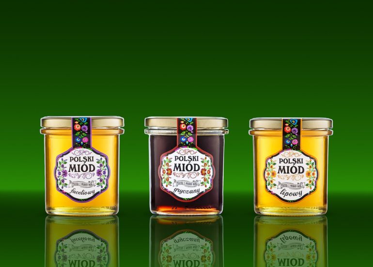 Trzy słoiki miodu na zielonym tle z lustrzanym odbiciem fotograf produktowy Olsztyn