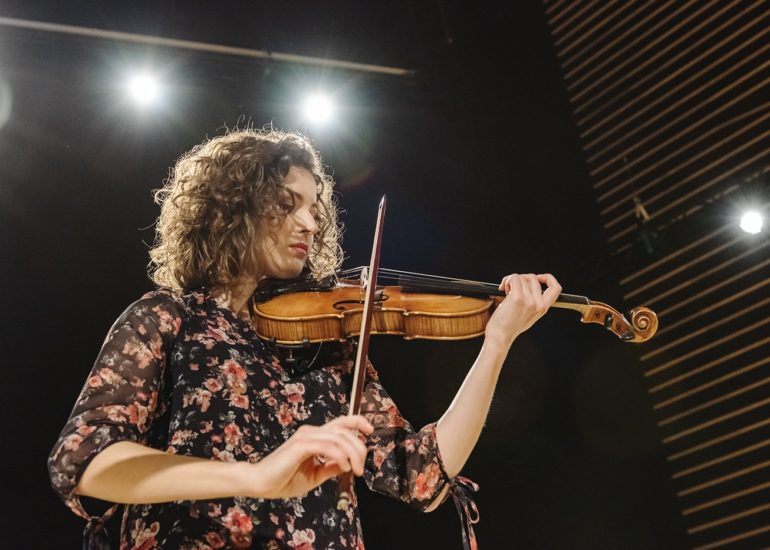 Skrzypaczka w trakcie koncertu w Filharmonii Warmińsko-Mazurskiej w Olsztynie na tle jupiterów - fotografia eventowa